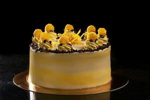 il giro giallo compleanno torta. decorativo crema decorazioni su il torta. nero sfondo. foto