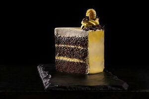 pezzo di giallo compleanno torta. decorativo crema decorazioni su il torta. nero sfondo. foto