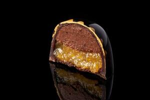 tagliare lusso fatto a mano caramella con cioccolato e giallo confiture Riempimento su nero sfondo. foto