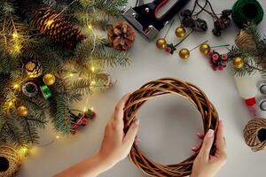 femmina mani decorare il Natale ghirlanda con abete rosso rami con un' rosso bacca e foresta coni. bianca sfondo. nuovo anni concetto. foto