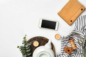 ancora vita con tè tazza e il Contenuti di un' spazio di lavoro composto. diverso oggetti su bianca tavolo. piatto posare foto