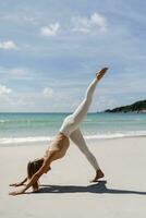 grazioso donna indossare bianca abbigliamento sportivo praticante yoga su spiaggia nel Tailandia. sensazione così confortevole e rilassare nel vacanza, sano concetto. foto