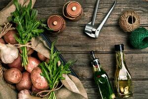 fresco patate, olio, aglio e speziato erbe aromatiche su un' cucina di legno sfondo. foto