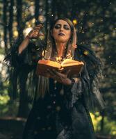 travolgente strega nel un' misterioso Halloween foresta, evocazione Magia con un' ardente Libro degli incantesimi nel un' spaventoso atmosfera foto