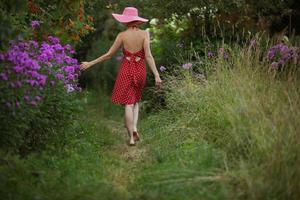 donna con cappello cammina tra i fiori foto