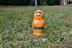 un' piccolo di legno Bambola seduta nel il erba foto