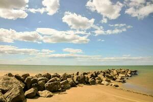 un' roccioso spiaggia con un' grande roccia parete e blu cielo foto