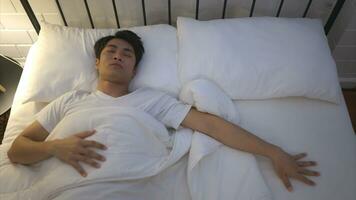 giovane asiatico uomo dire bugie su il letto uso il suo mano per armeggiare il suo moglie chi pensa sua svegliato su insieme quello mattina. foto