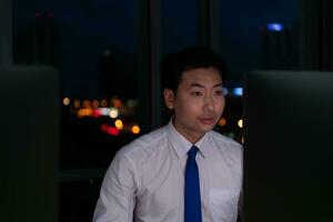 ritratto di giovane asiatico uomo d'affari Lavorando nel ufficio a notte. attività commerciale e tecnologia concetto. foto