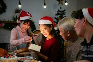 contento asiatico famiglia festeggiare Natale a casa. con il attività di dando i regali per ogni altro tra famiglia membri foto