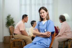 ritratto di asiatico femmina infermiera utilizzando digitale tavoletta nel assistenza infermieristica casa con anziano persone su sfondo foto
