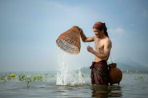 pescatore utilizzando tradizionale pesca Ingranaggio per catturare pesce per cucinando, rurale Tailandia vivente vita concetto foto