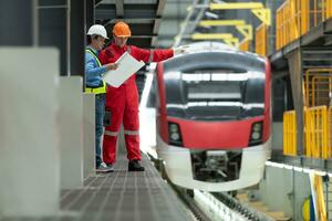 dopo il elettrico treno è parcheggiata nel il elettrico treno riparazione negozio, elettrico treno ingegnere e tecnico con utensili ispezionare il ferrovia e elettrico treni nel conformità con il ispezione il giro foto