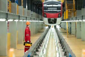 elettrico veicolo ingegnere con cassetta degli attrezzi ispezionare il macchinari di il elettrico treno secondo per il ispezione il giro. dopo il elettrico treno era parcheggiata nel il elettrico del treno riparazione negozio foto