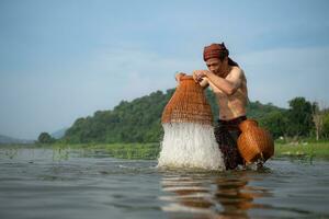 pescatore utilizzando tradizionale pesca Ingranaggio per catturare pesce per cucinando, rurale Tailandia vivente vita concetto foto