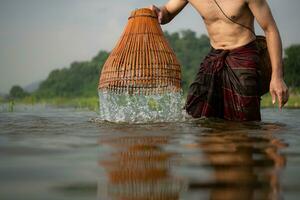 pescatore utilizzando tradizionale pesca Ingranaggio per catturare pesce per cucinando, rurale Tailandia vivente vita concetto foto