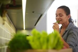 piacevole casalinga mangiare spinaci partire mentre ordinamento verdure e verdura nel cartone scatola su il primo piano foto