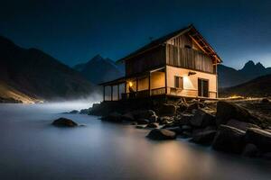 un' piccolo Casa si siede su il riva di un' lago a notte. ai-generato foto