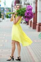 un' bellissimo anziano donna con un' mazzo di fiori passeggiate attraverso il strade di il città. età modello bionda nel pieno crescita. un' donna nel sua anni Cinquanta nel un' bellissimo vestire. foto