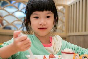 carino poco asiatico bambino ragazza mangiare cibo foto