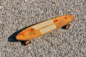 un' di legno skateboard posa su ghiaia foto