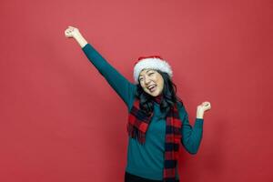 bella sorridente asiatico donna nel caldo Natale maglione e Santa cappello su rosso sfondo per stagione celebrazione concetto foto