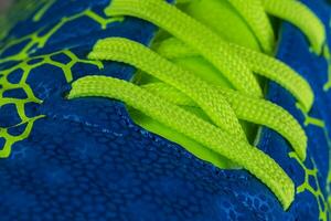 frammento di un' blu sneaker con verde lacci vicino su. sneaker struttura foto