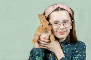 divertente ragazza nel bicchieri abbracci un' coniglio e sorrisi. foto