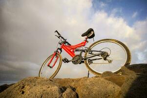 un' rosso montagna bicicletta è seduta su superiore di un' roccia foto