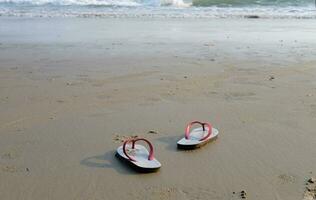 sandali e scarpe impronte su il spiaggia e blu mare. foto