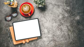 ufficio scrivania posto di lavoro con vuoto schermo tavoletta, taccuino, penna, monocolo e tazza di caffè, superiore Visualizza piatto posare con copia spazio. foto