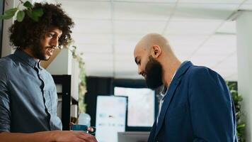 ufficio lavoratori incontro su opera rompere, ridendo insieme e godendo tazza di caffè. Due attività commerciale partner scherzando in giro e avendo divertimento nel coworking Aperto spazio ufficio, lavoro collaborazione. foto