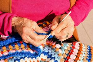 un più vecchio donna è maglieria un' colorato uncinetto coperta foto