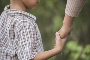 primo piano di mamma e figlio felici che si tengono per mano in un parco. concetto di famiglia. foto