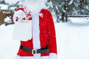 Santa Claus all'aperto nel inverno e neve passaggio nel mano carta borse con mestiere regalo, cibo consegna. acquisti, confezione raccolta differenziata, fatto a mano, consegna per Natale e nuovo anno foto