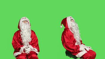 padre Natale seduta su sedia al di sopra di isolato schermo verde sfondo, Santa Claus incarnazione con rosso e bianca costume. gioioso uomo pubblicità di stagione vacanza celebrazione concetto. foto