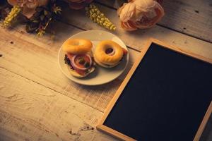 lavagna di legno vuota della scuola sul pavimento di legno con pane dell'hamburger foto