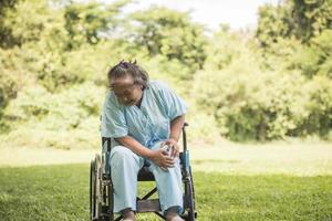 donna anziana seduta su sedia a rotelle con dolore al ginocchio foto