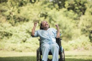 donna anziana solitaria seduta su sedia a rotelle in giardino in ospedale