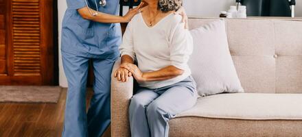 contento giovane femmina infermiera fornire cura medico servizio Aiuto supporto sorridente vecchio nonna a cura della casa medico visitare, signora badante medico dare empatia incoraggiare pensionato paziente sedersi su divano a casa ospedale foto