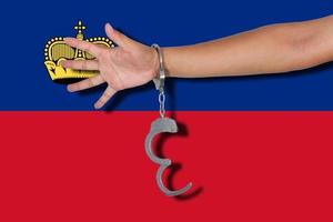 manette con la mano sulla bandiera del Liechtenstein foto