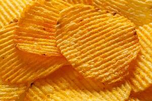 macro di bellissimo ondulato giallo patatine fritte sotto il di sole raggi foto