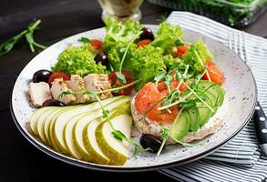 salutare prima colazione. panini con crema formaggio, salmone, avocado e fetta Pera su piatto. foto