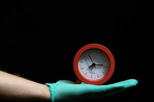 un' persona nel un' verde guanto Tenere un' orologio foto