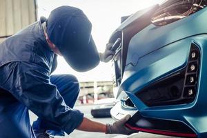 meccanici che installano la gonna anteriore nel garage dell'officina riparazioni auto foto