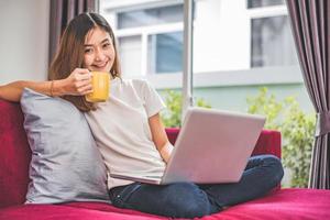 la donna asiatica si diverte mentre usa internet su laptop e telefono