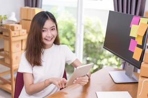 donna asiatica che utilizza tablet con scatole di pacchi nel tema del servizio di consegna foto