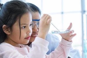 ragazza scienziata e insegnante che fa cadere la sostanza liquida pipetta foto