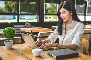donna asiatica che lavora con il computer portatile nella caffetteria? foto