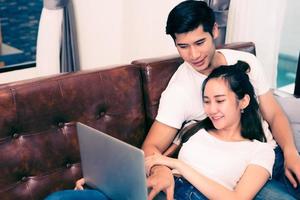 giovani coppie asiatiche che per mezzo del computer portatile. amanti e coppie foto